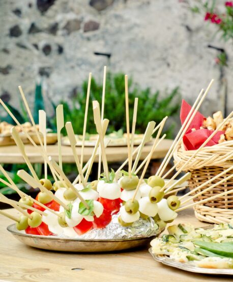 Buffet mit Mozzarella-Spießen und Brotgebäck auf Holztischen im Freien